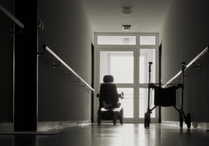 Pearland Nursing Home Abuse Lawyer - empty wheelchair sits at the end of a dark hallway with light at end