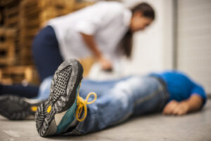 Woman leans over man lying on ground after an accident with cellphone in hand, ready to call a Slip And Fall Lawyer Houston, TX